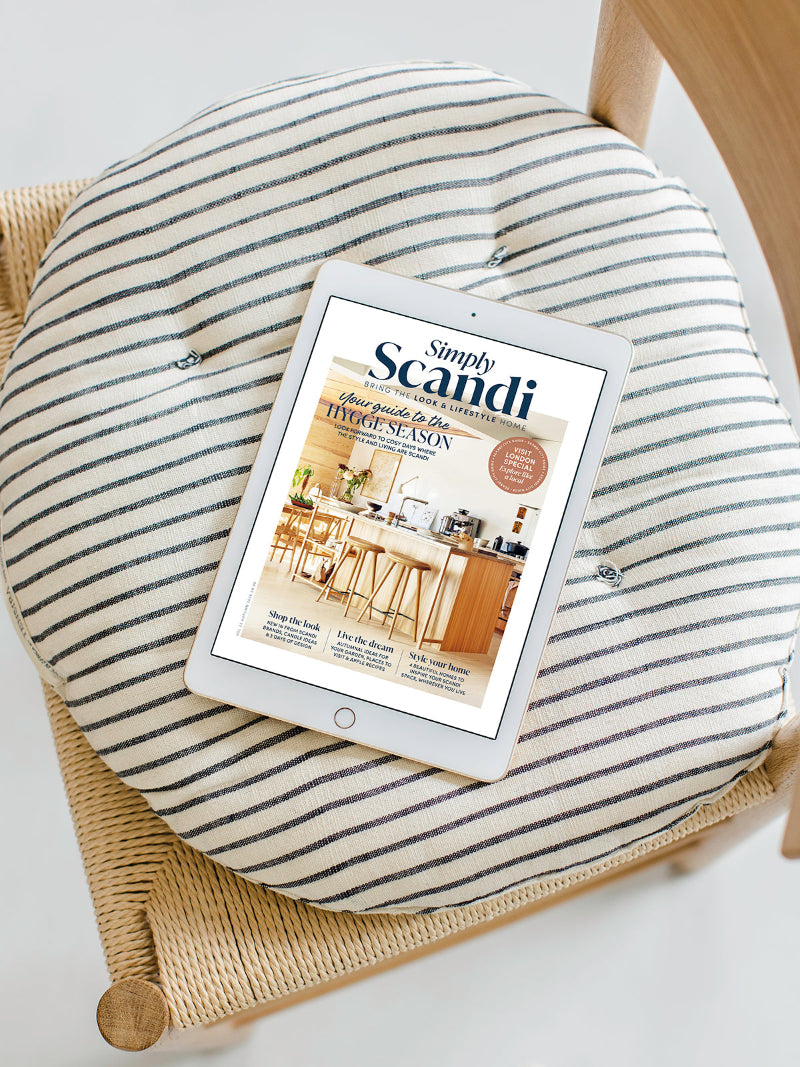 A round striped cushion on a woven chair with an iPad displaying the magazine cover 'Simply Scandi' resting on top.