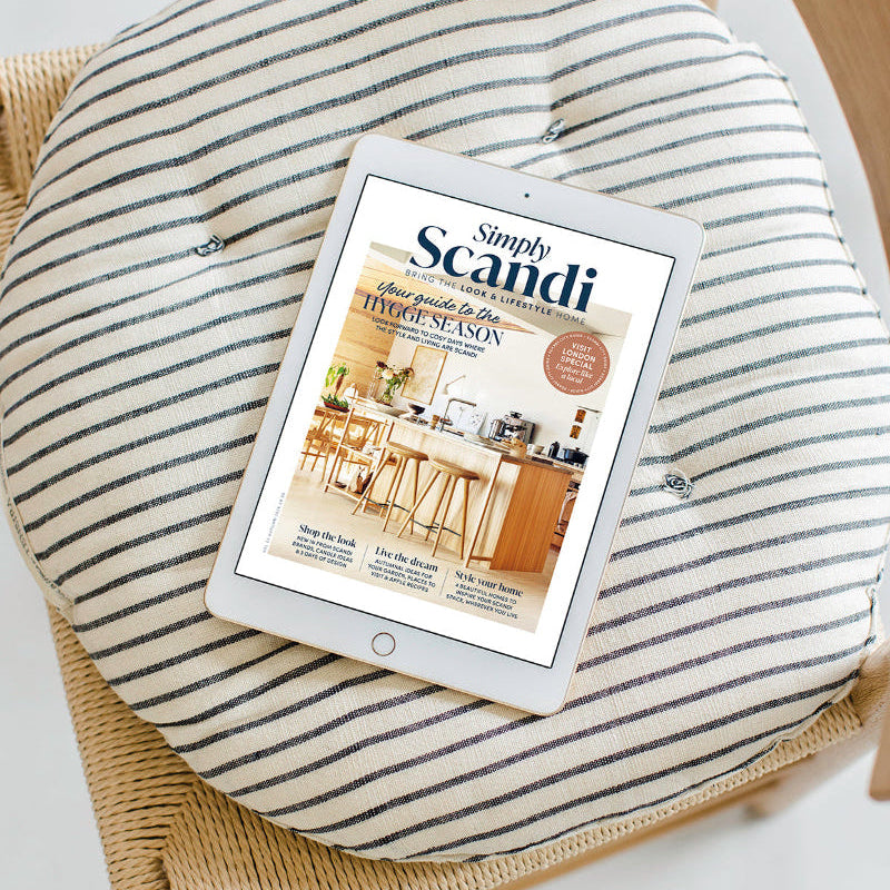 A round striped cushion on a woven chair with an iPad displaying the magazine cover 'Simply Scandi' resting on top.